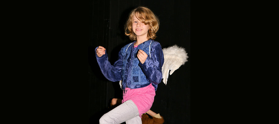 Ein Kind als Engel verkleidet auf der Theaterbühne